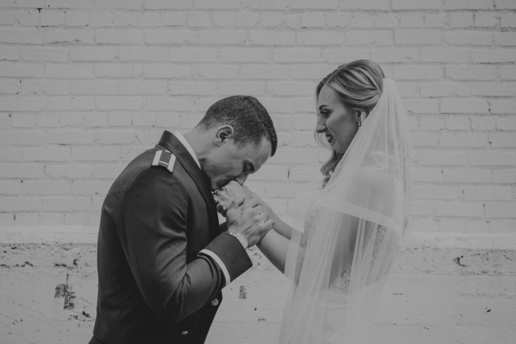 A groom kisses his bride's hands on their wedding day.