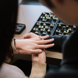 A customer tries on potential ring options with many rings to choose from.